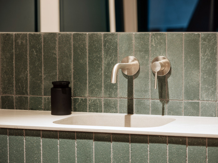 Close-up of the basin and green wall tiles at Nortal office
