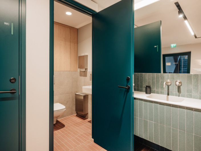 Nortal office restroom with green tiles and red herringbone-pattern flooring