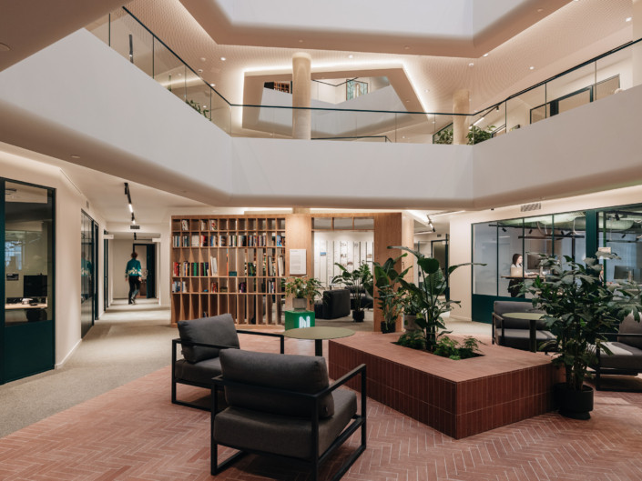 Atrium seating area with reddish tiled flooring and plants at Nortal office