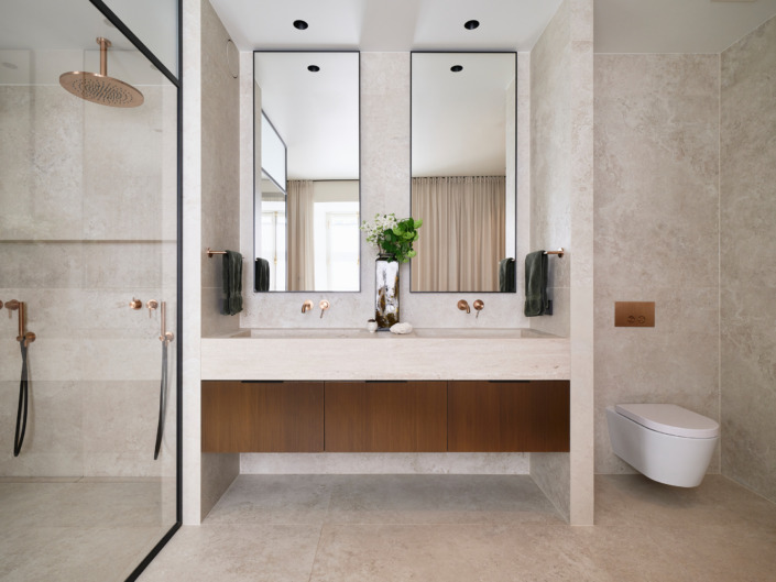 Light bathroom with two mirrors and a glass shower enclosure in the Old Town apartment